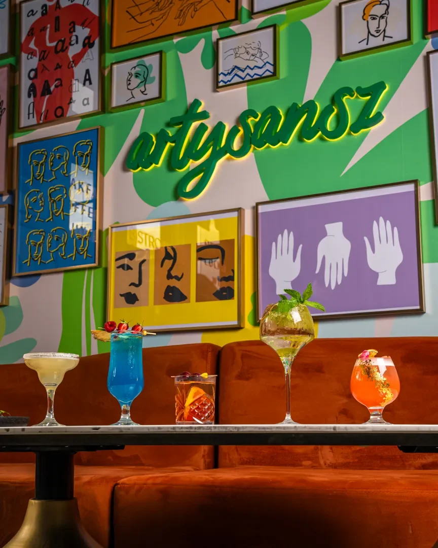 Five cocktails in front of the neon Artysansz wall