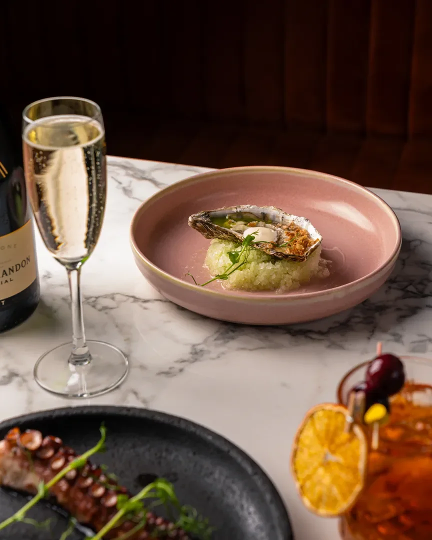 Oyster, grilled octopus, prosecco and a spritz on a marble table